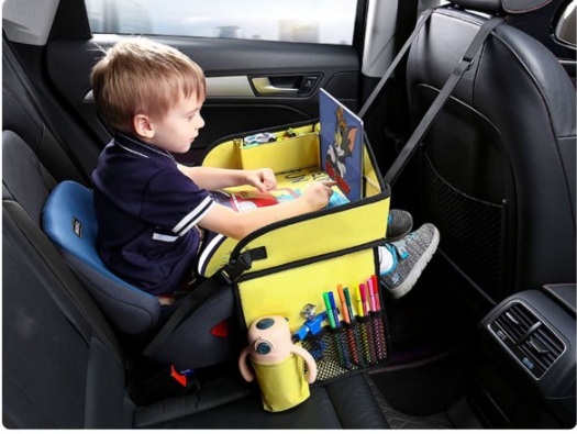 Child using a tablet on a raised-sided travel tray in the back seat