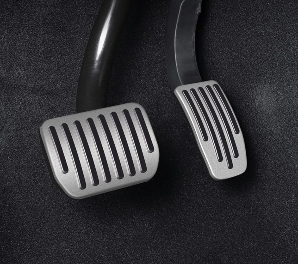 Silver Tesla brake and accelerator pedal covers installed in a dark footwell