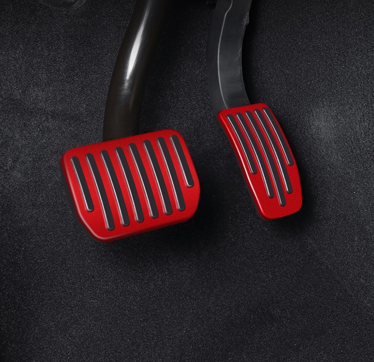 Red Tesla brake and accelerator pedal covers installed in a dark footwell